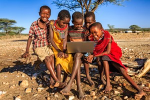 family in africa outside watching tv on laptop