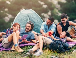 gorup of yuourg people outside camping with connectivity enjoying mobile devices